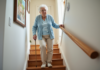 Cannes et escaliers : comment monter en toute sécurité avec ce handicap ? Femme âgée montant un escalier intérieur avec une canne